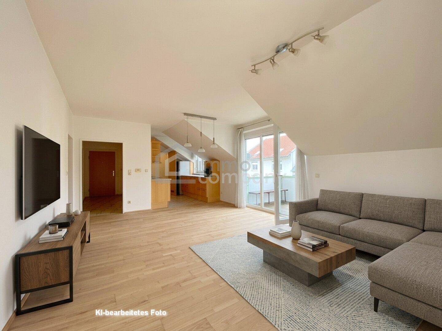 Helles Wohnzimmer mit Dachschräge, Holzboden und Zugang zu einem Balkon.