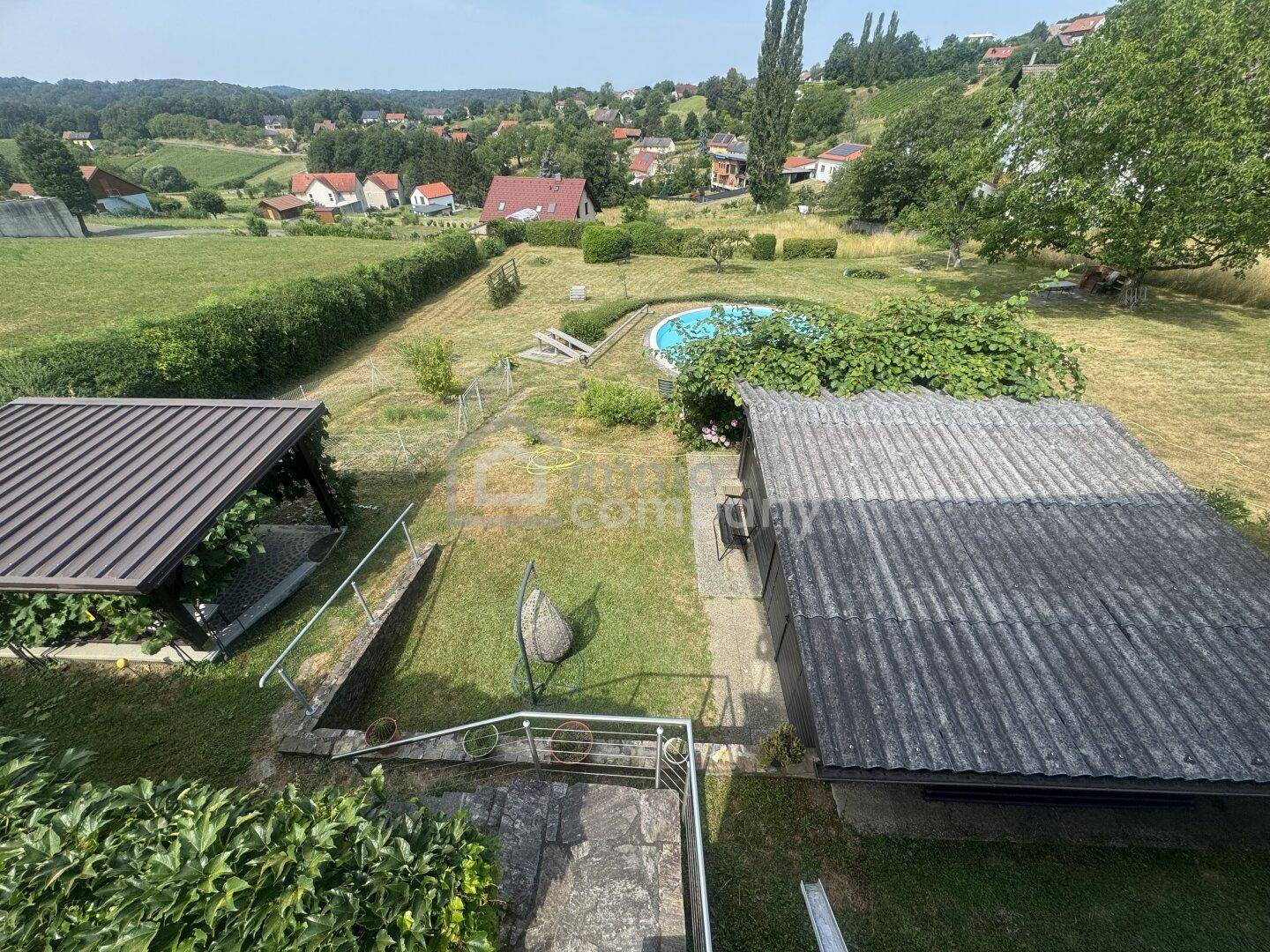 Weitläufiger Gartenbereich mit Pool, Liegewiese und Blick auf die umliegende Landschaft.