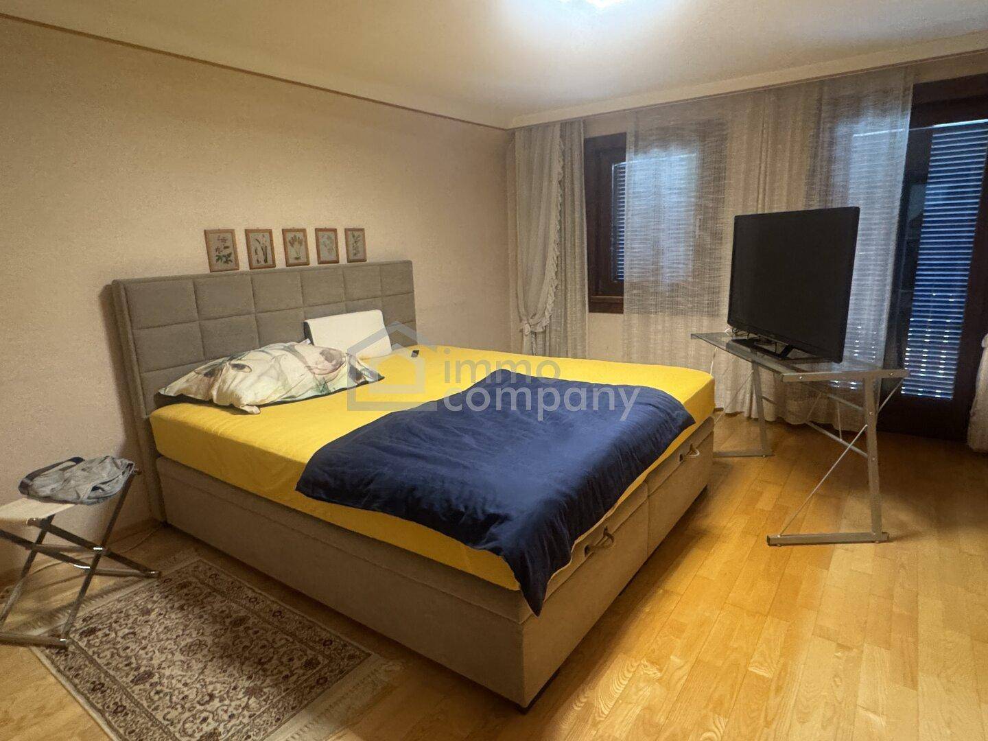 Schlafzimmer mit Doppelbett, Holzboden und Fenster mit Jalousien, hell und gemütlich.