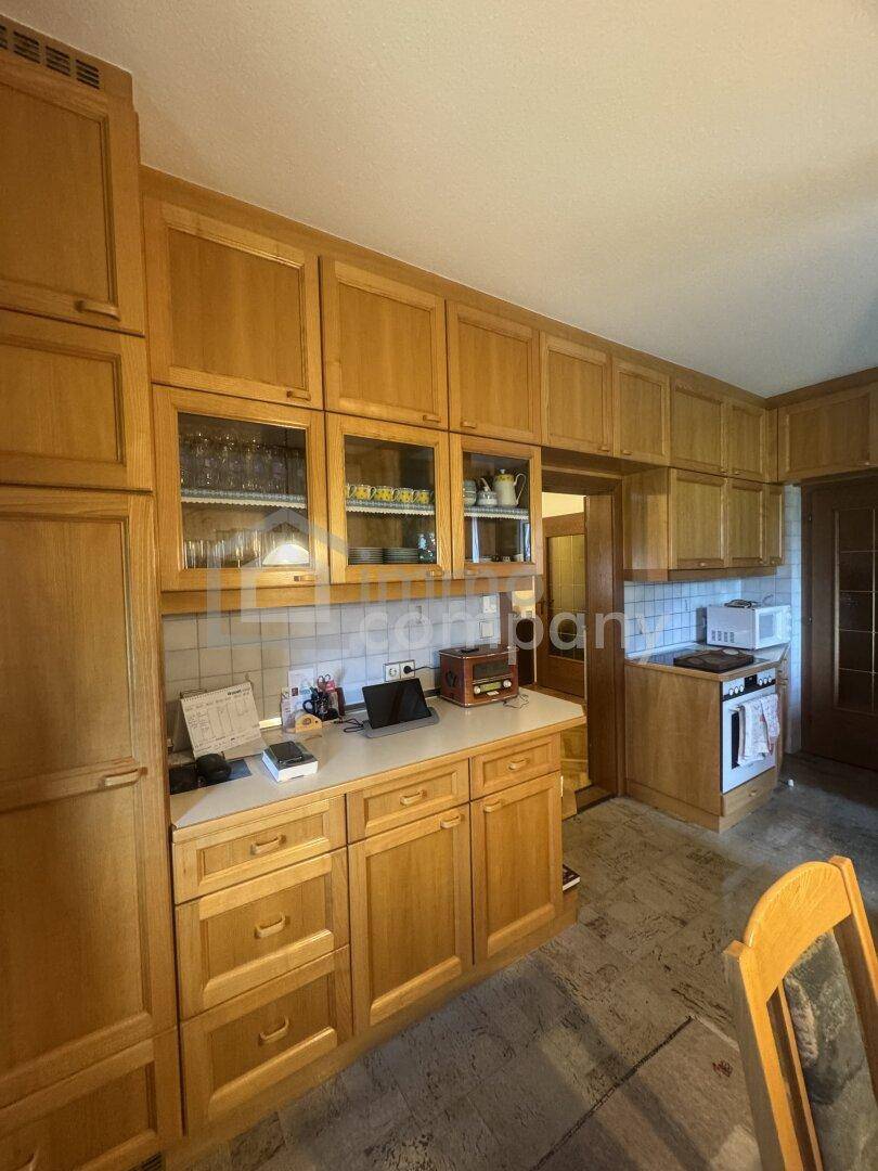 Geräumige Küche mit vielen Holzschränken, Arbeitsplatte und integrierten Geräten.
