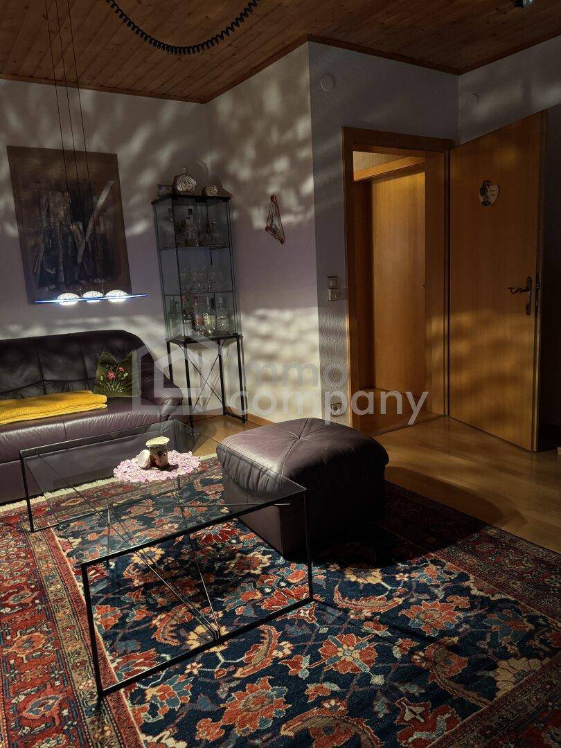 Gemütliches Wohnzimmer mit Ledersofa, Teppich und indirekter Beleuchtung, warm und einladend.
