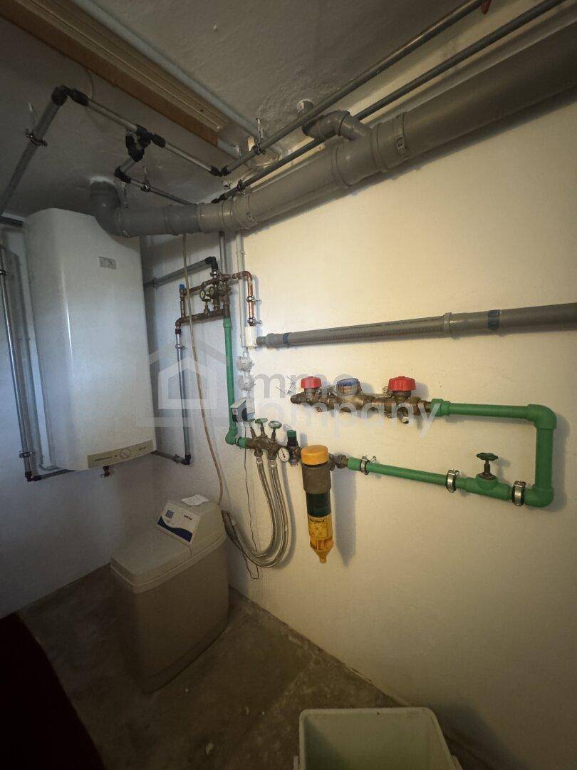 Technikraum mit Heizungsanlage, Wasserleitungen und Boiler, funktional und aufgeräumt.