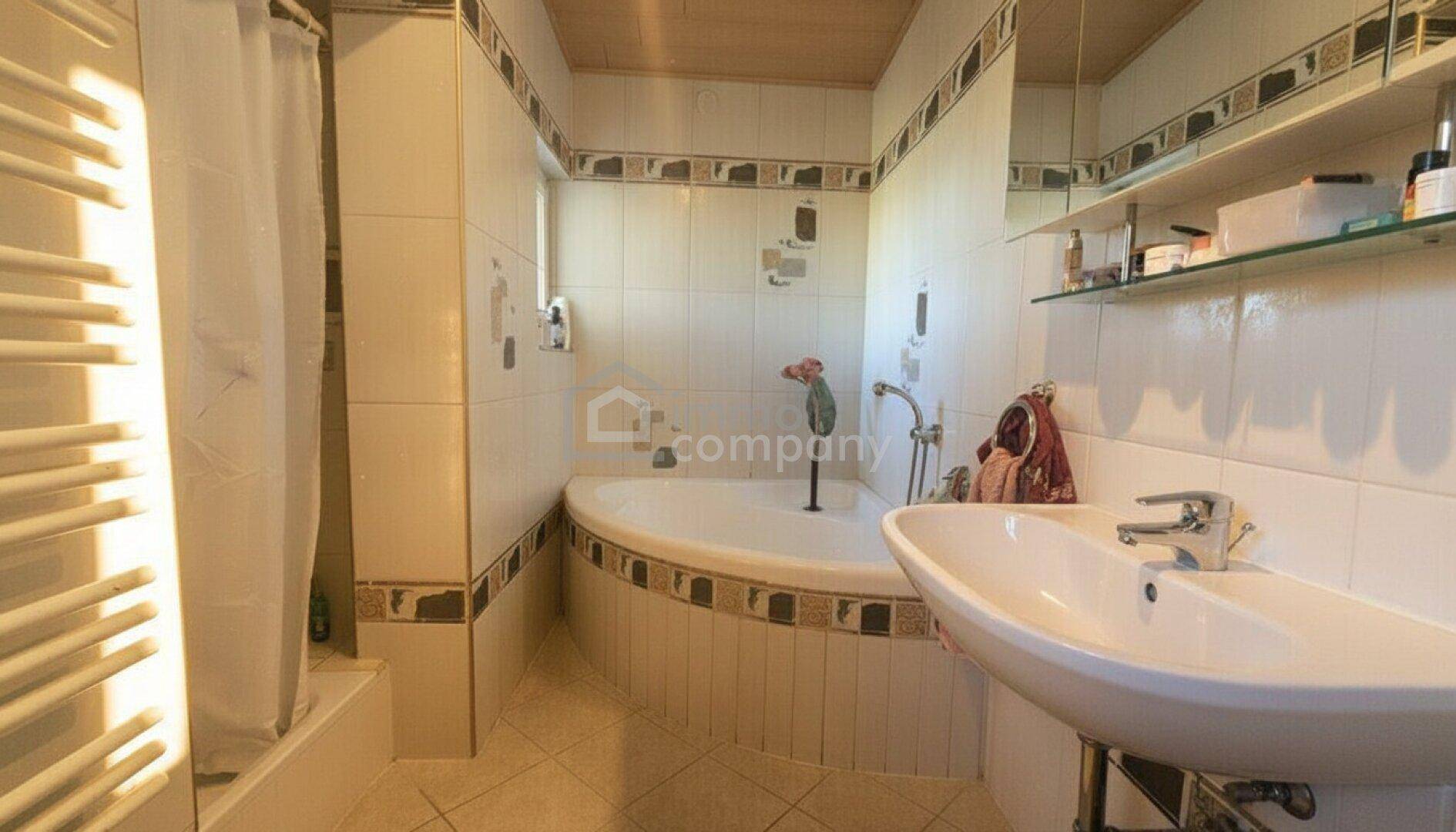 Badezimmer mit Eckbadewanne, separater Dusche und gefliesten Wänden in hellem Design.