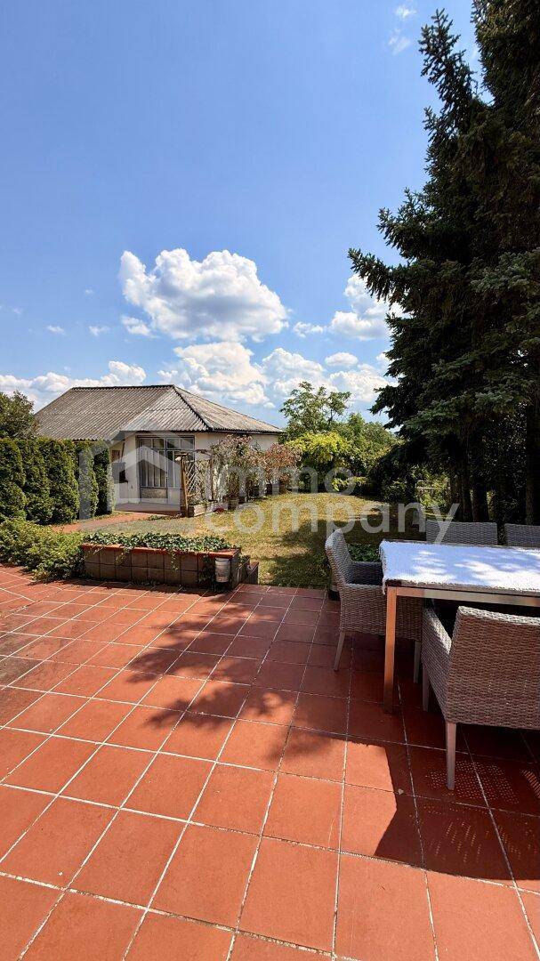 Große Terrasse mit Terrakottafliesen und Essbereich im Freien, mit Blick auf das Haus.