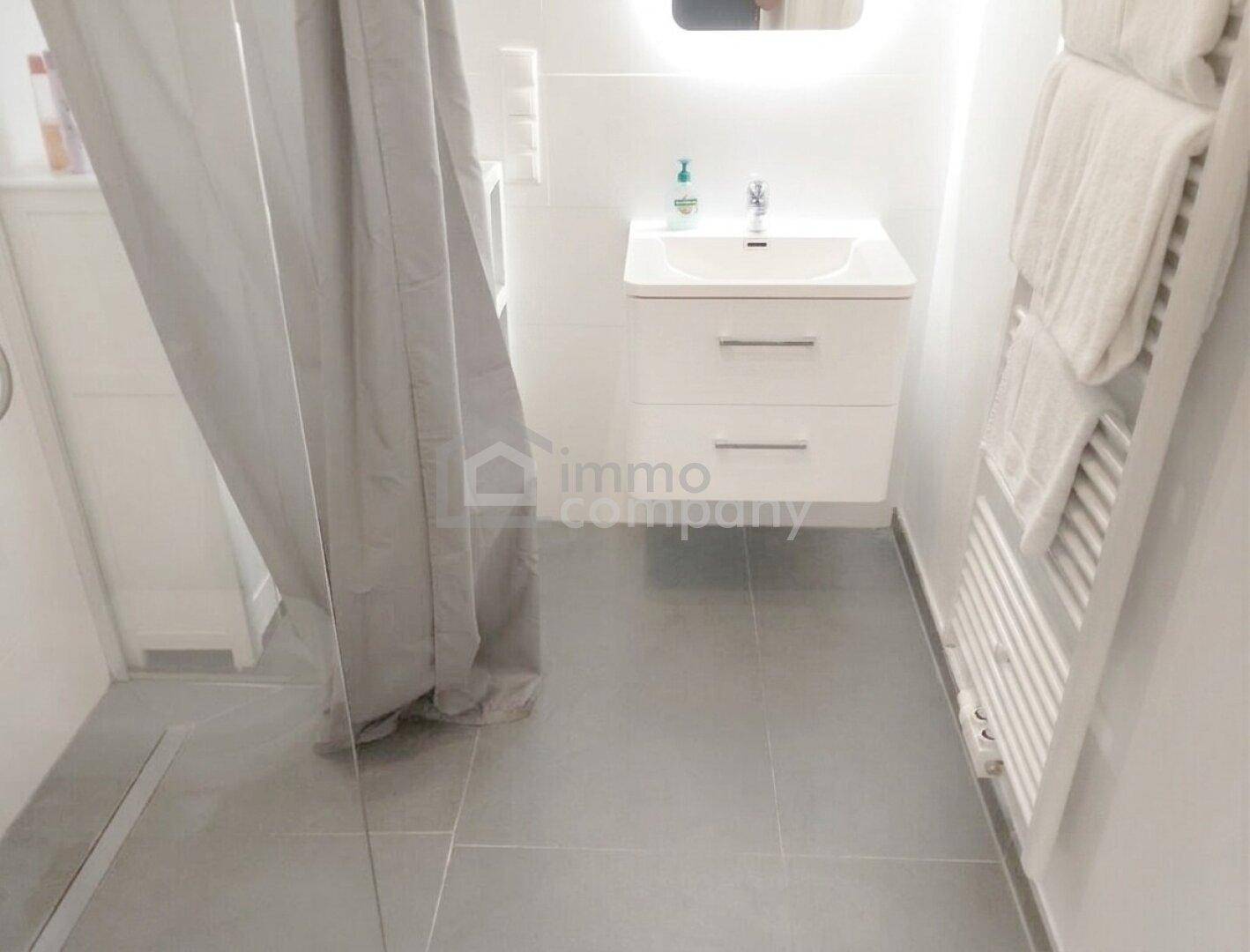 Helles Badezimmer mit Waschtisch, beleuchtetem Spiegel und beheiztem Handtuchhalter.