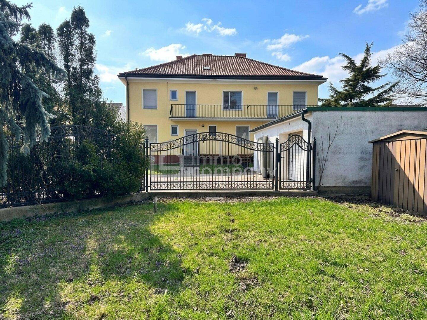 Rückansicht des Hauses vom Garten aus mit schmiedeeisernem Tor und Nebengebäude.