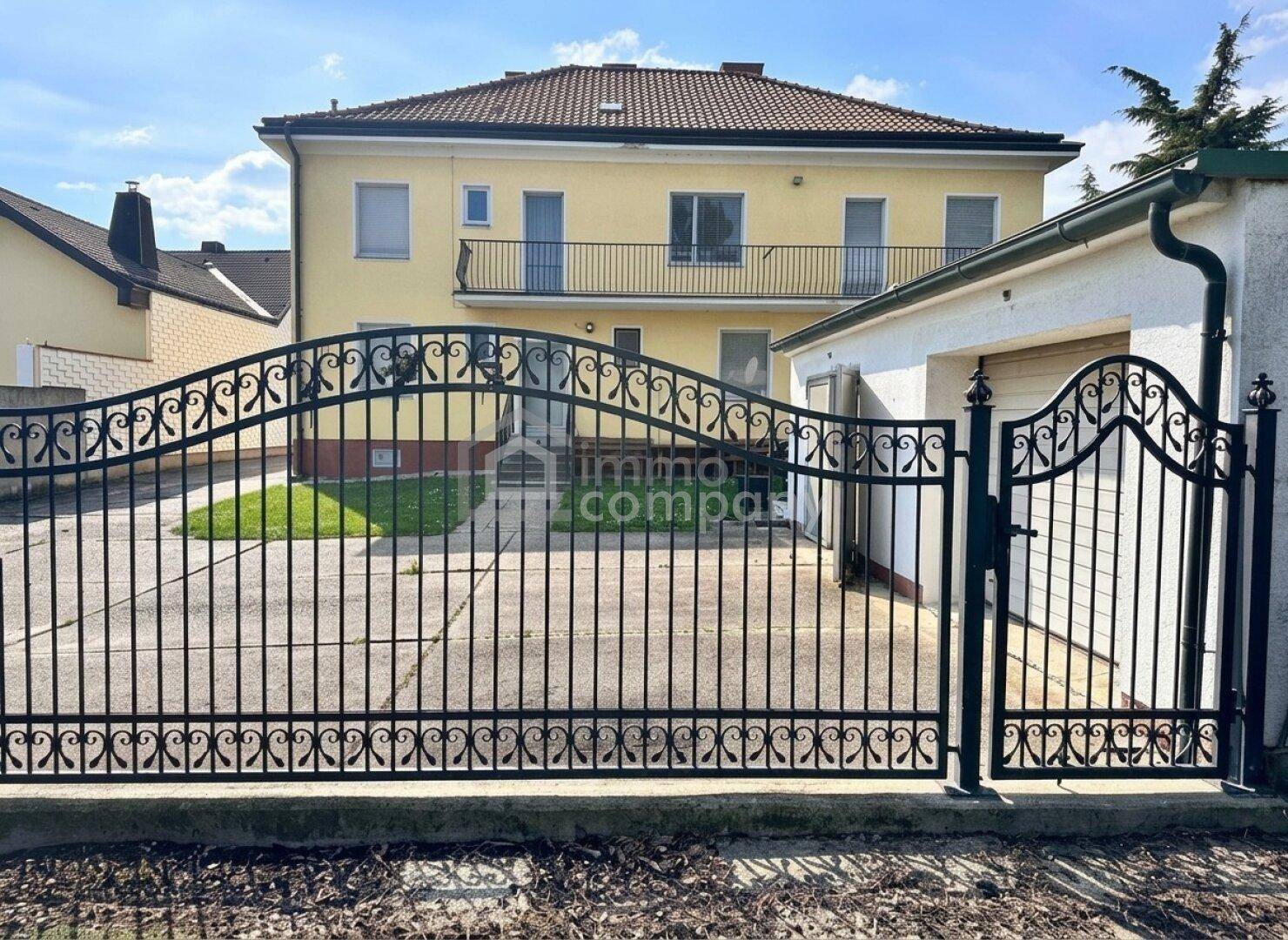 Einfahrt mit schmiedeeisernem Tor und Zugang zur Garage hinter dem Haus.