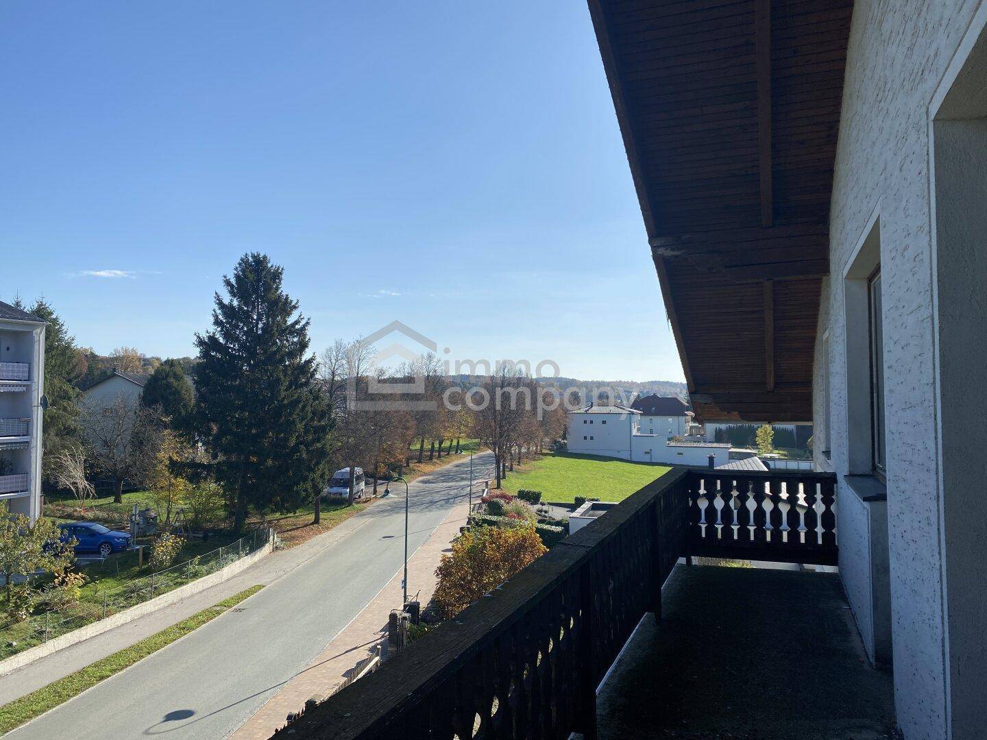 Balkon mit traditionellem Holzgeländer und weitem Blick über die Straße und die umliegende Landschaft.