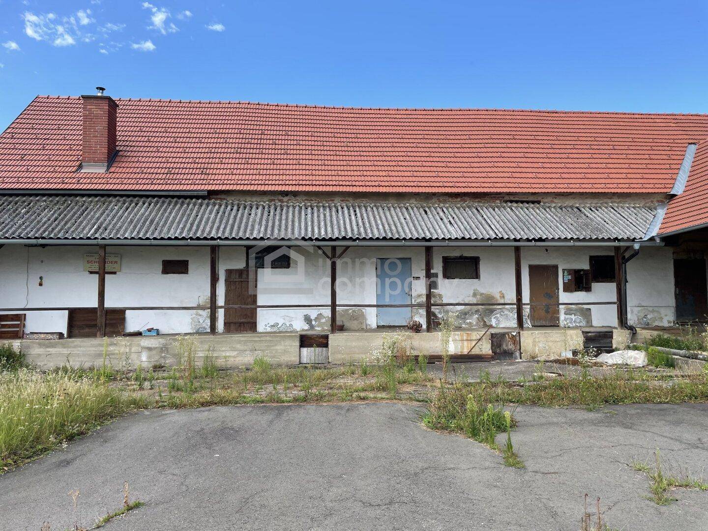 Langes, altes Wirtschaftsgebäude mit rotem Ziegeldach und verwitterter Fassade.