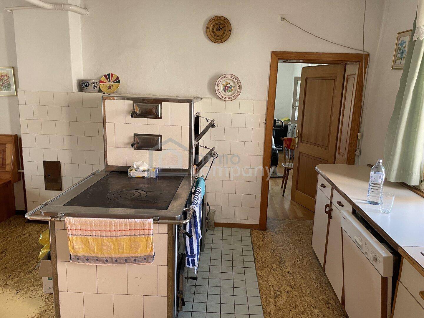 Rustikale Küche mit traditionellem Kachelofen, Spülbecken und Holztüren.