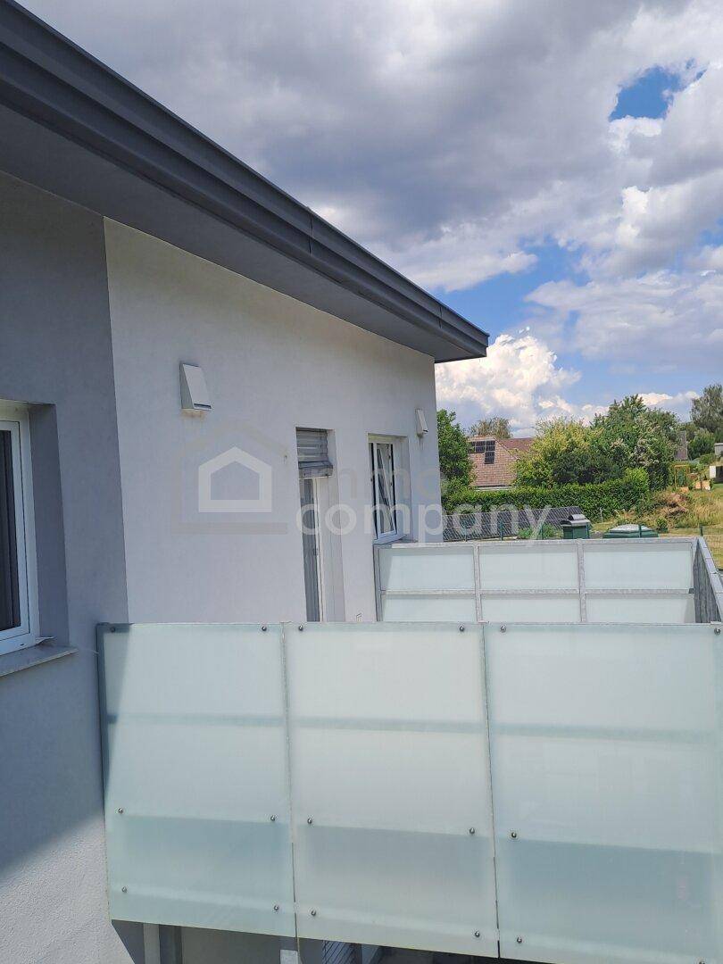 Außenansicht des Gebäudes mit Balkonbrüstung unter bewölktem Himmel.