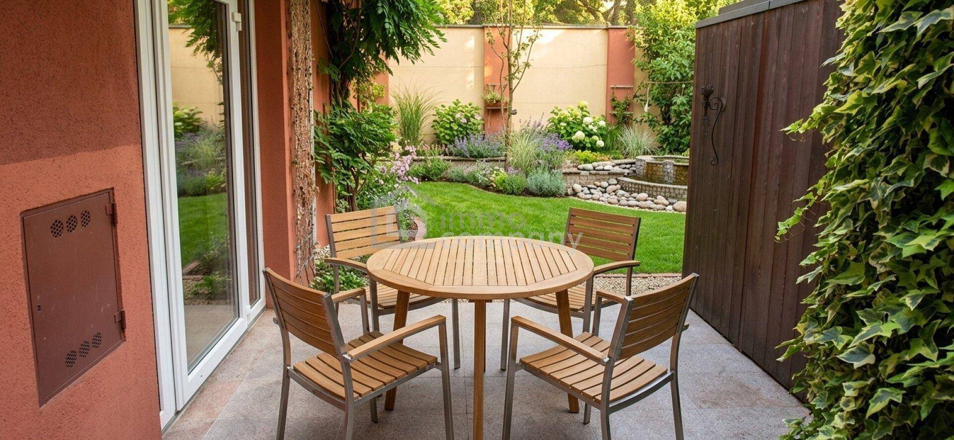 Gemütliche Terrasse mit Holztisch und Stühlen, umgeben von einem gepflegten Garten mit Bepflanzung.