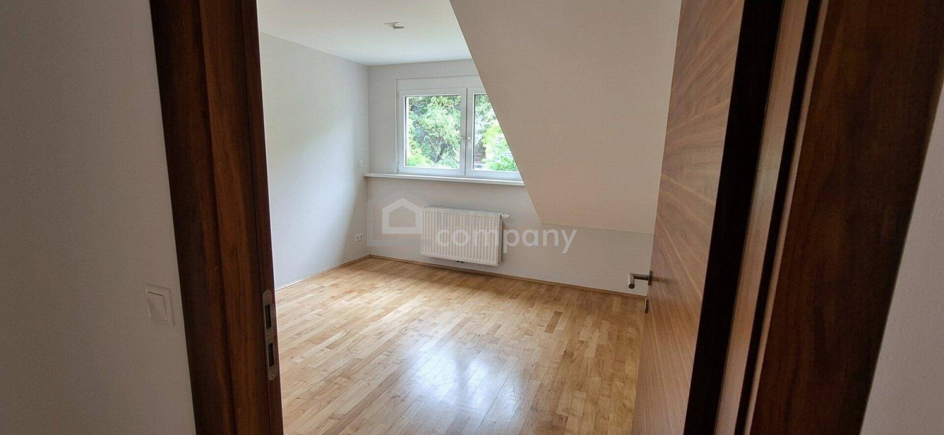 Helles Zimmer im Dachgeschoss mit Holzboden, Dachschräge und Fenster, bereit zur individuellen Gestaltung.
