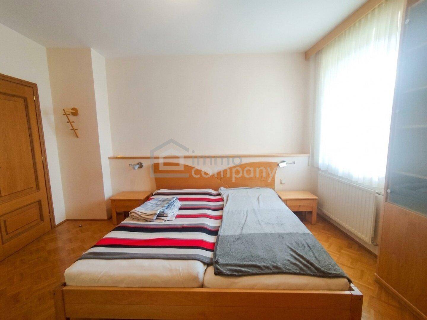 Gemütliches Schlafzimmer mit Doppelbett, Holzboden und großem Fenster für viel Tageslicht und frische Luft.