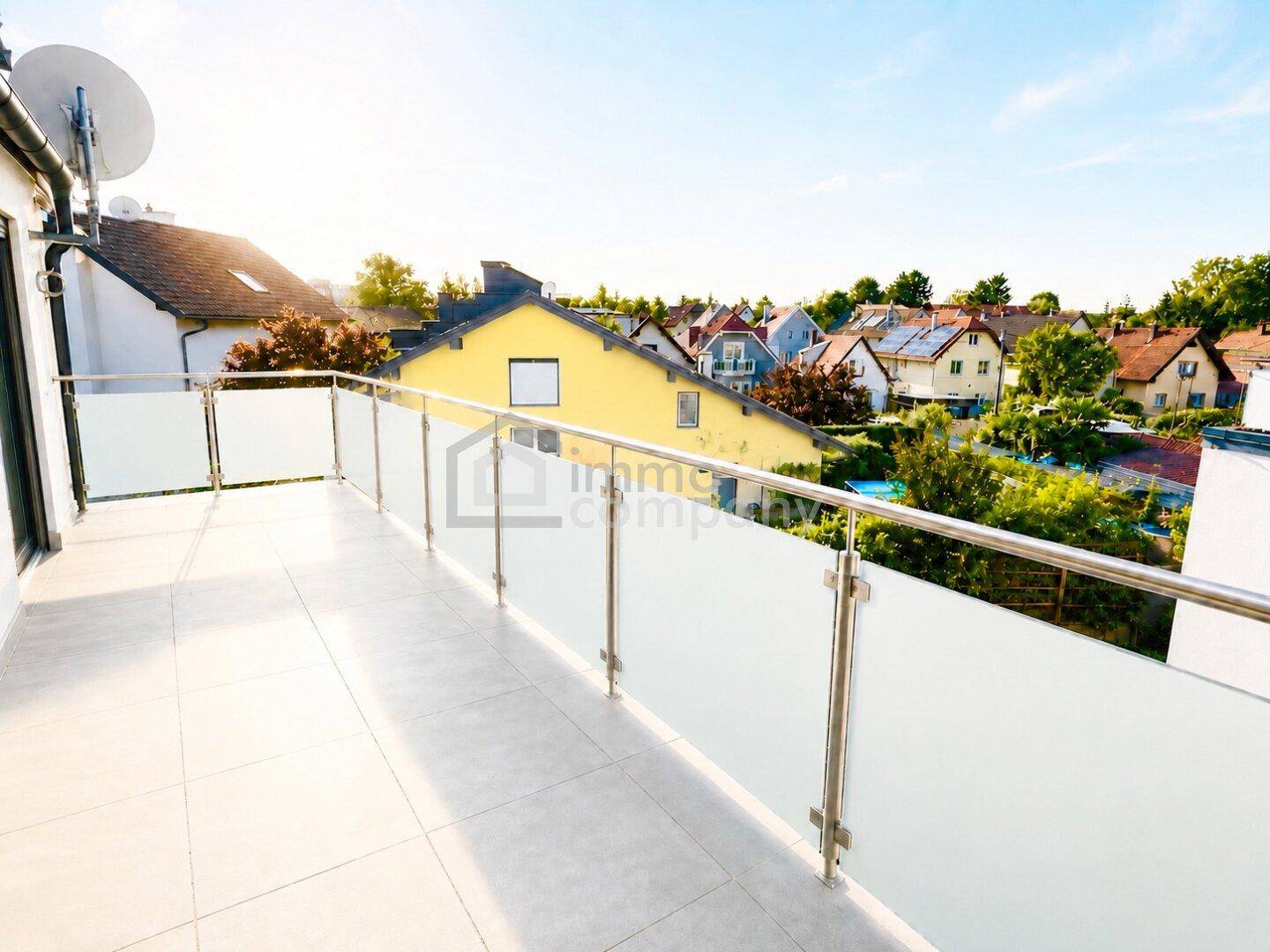 Geräumiger Balkon mit Glasgeländer und weitem Blick über die umliegende Wohngegend.