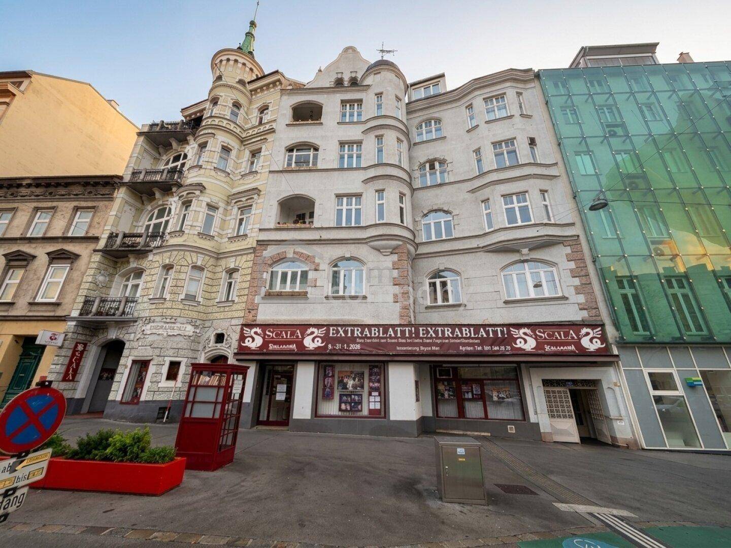 Historisches Gebäude mit verspielter Fassade neben einem modernen Bau mit Glasfront in urbaner Umgebung.