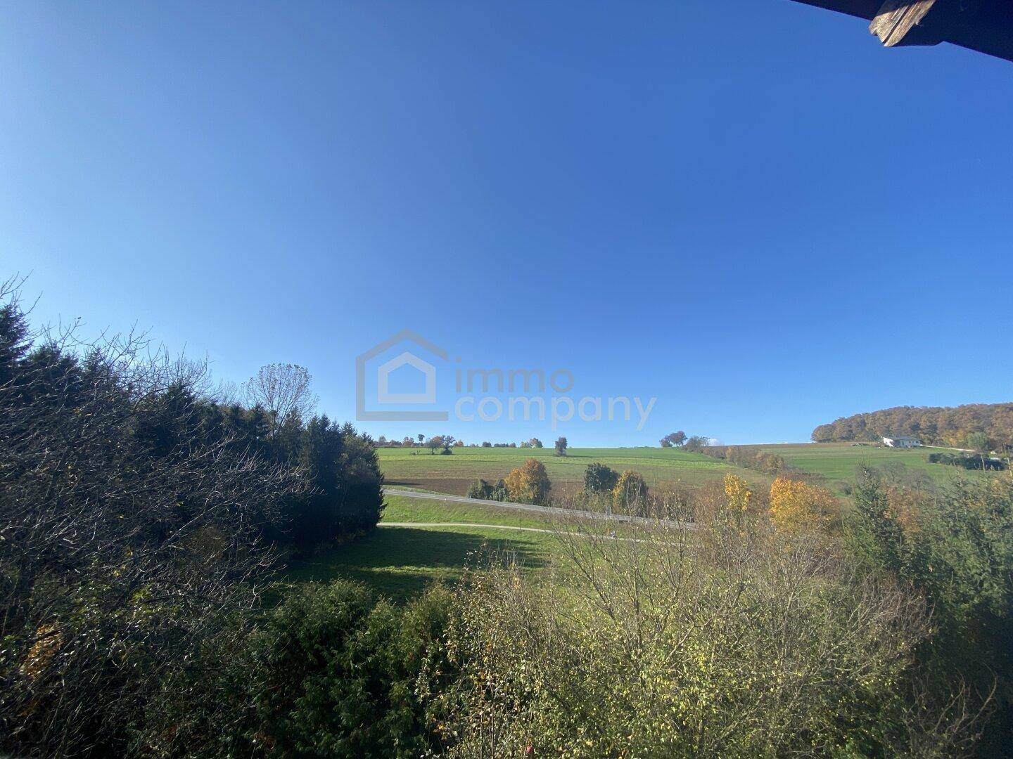 Weitläufiger Blick über Felder und Wälder unter einem strahlend blauen Himmel.