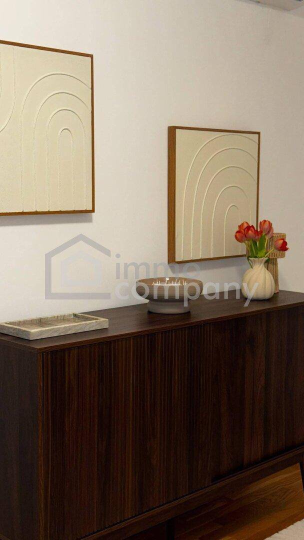 Modernes Sideboard aus dunklem Holz mit abstrakten Wandbildern und Dekoration.