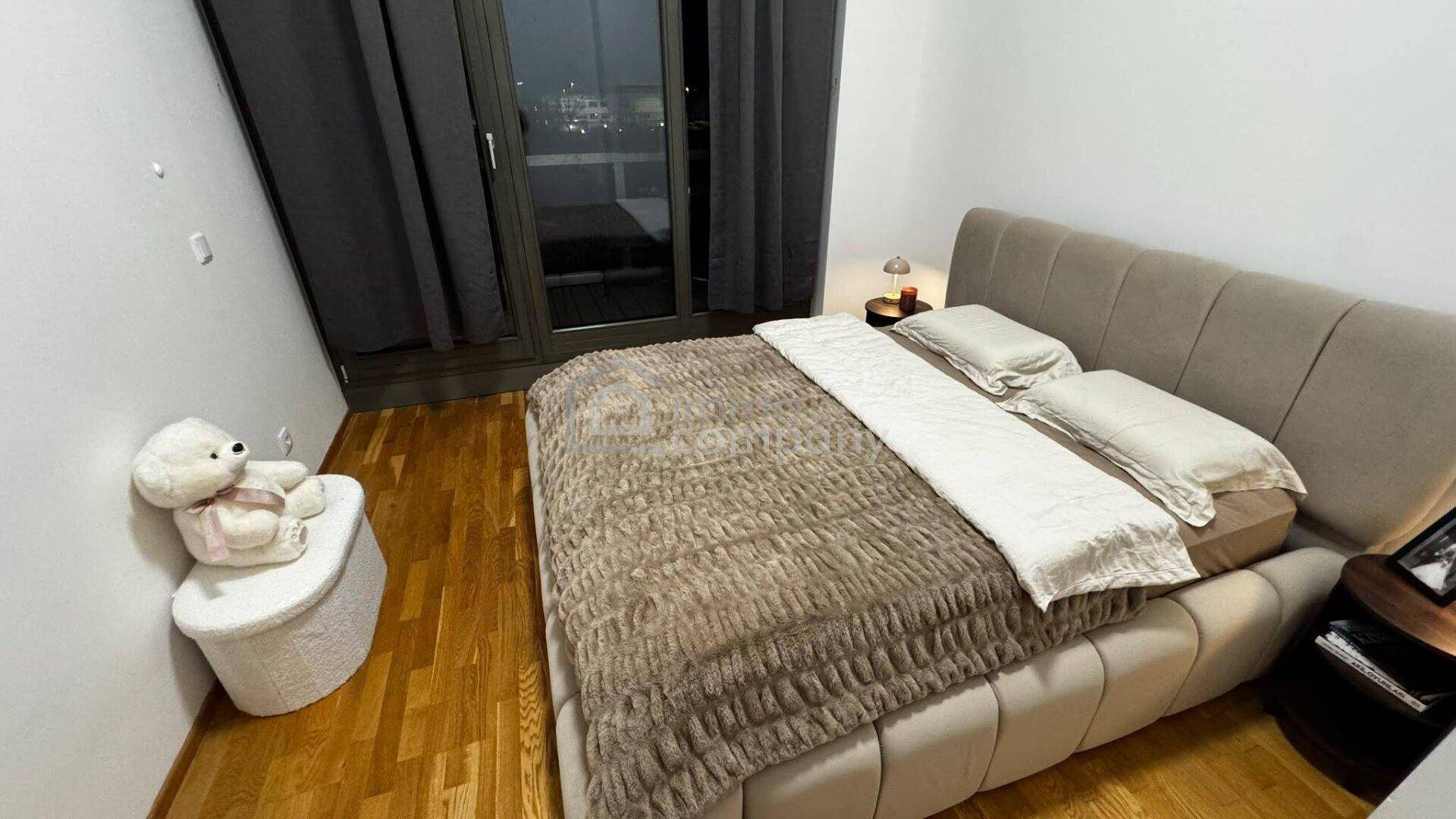 Gemütliches Schlafzimmer mit großem Bett, Holzboden und Zugang zu einem Balkon.