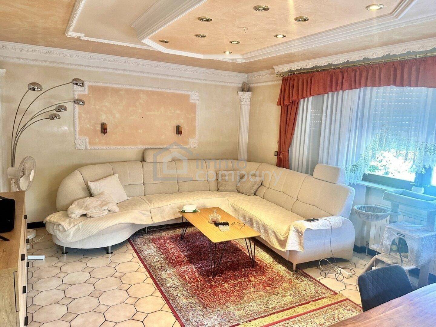 Gemütliches Wohnzimmer mit großem Ecksofa, Teppich und dekorativer Stuckdecke.