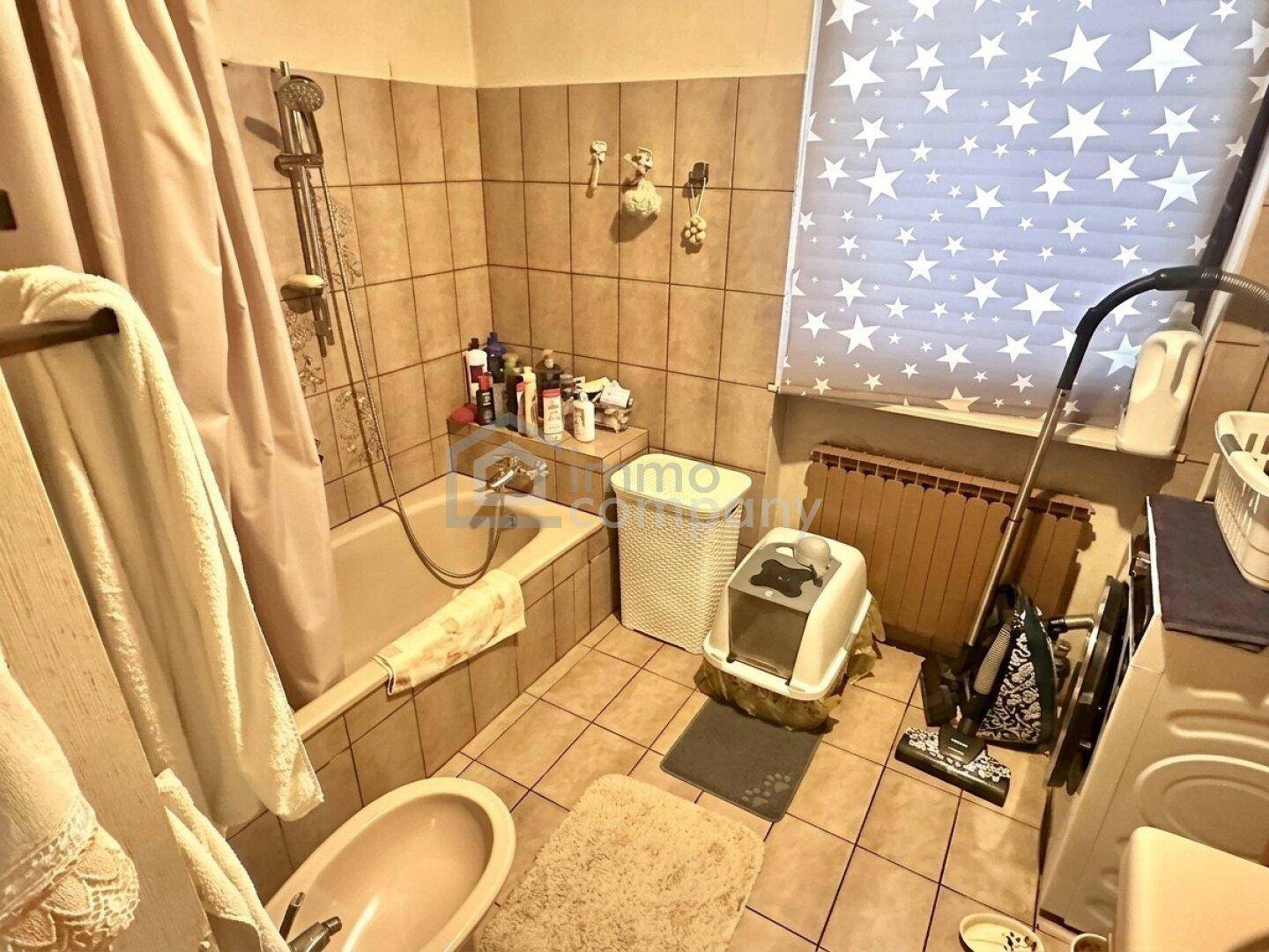 Badezimmer mit Badewanne, Bidet und Fliesenboden, ausgestattet mit einem Fenster.