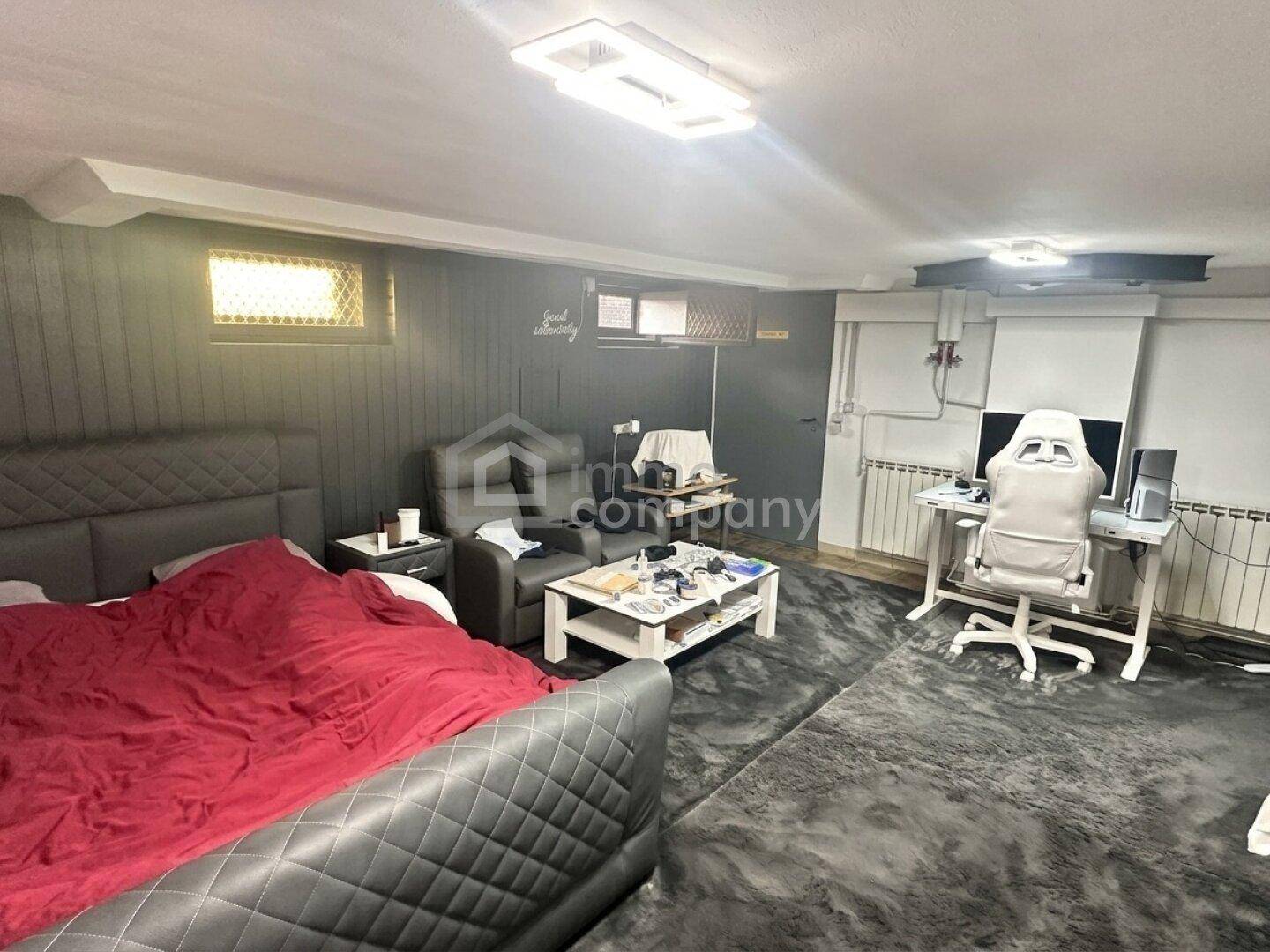 Geräumiger Kellerraum, eingerichtet als Schlafzimmer und Arbeitsbereich mit Teppichboden.