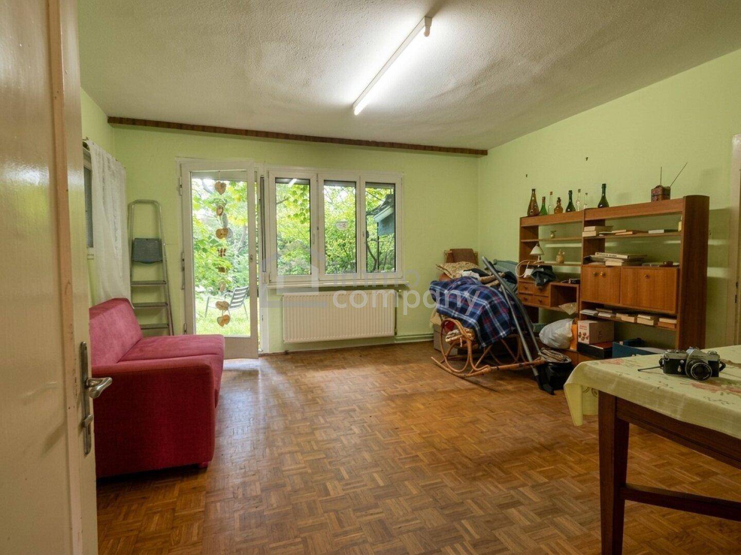 Helles Wohnzimmer mit Fischgrätparkett, grün gestrichenen Wänden und direktem Gartenzugang.