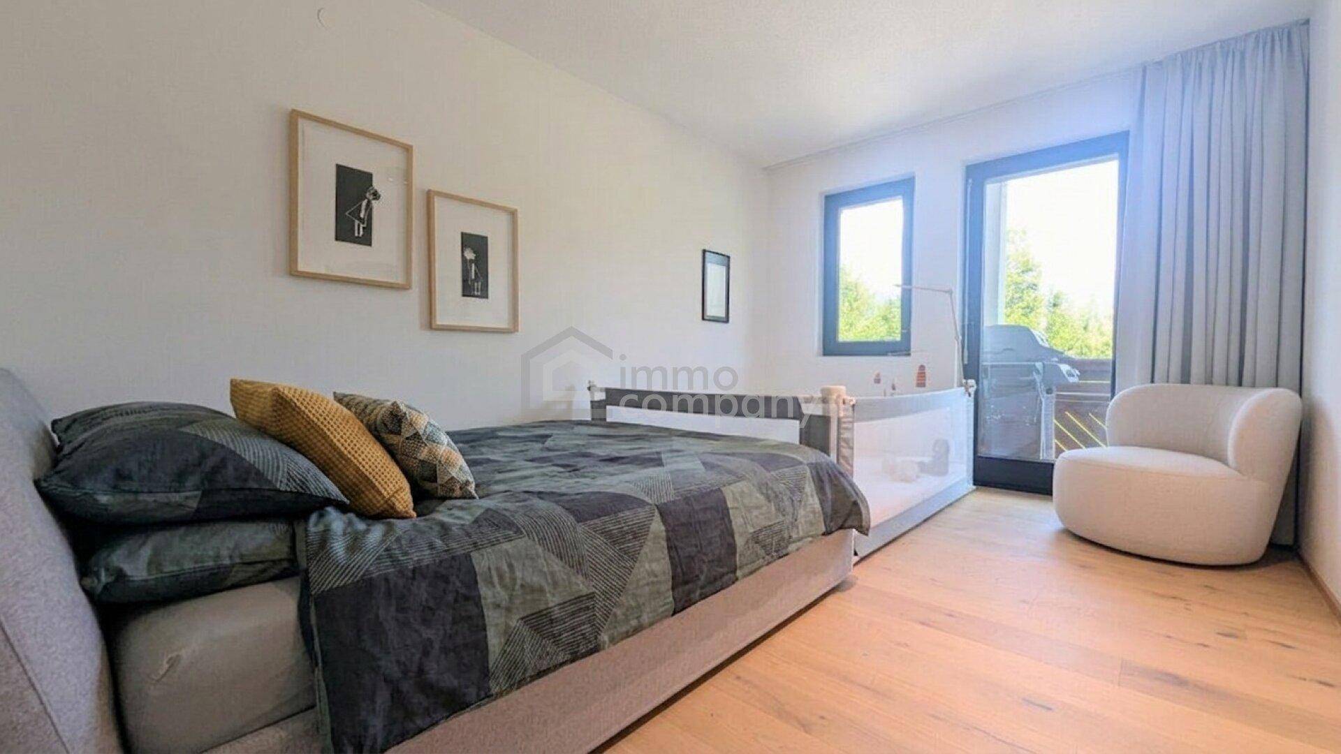 Helles Schlafzimmer mit Bett, Babybett und Zugang zu einem Balkon, ideal für Familien.
