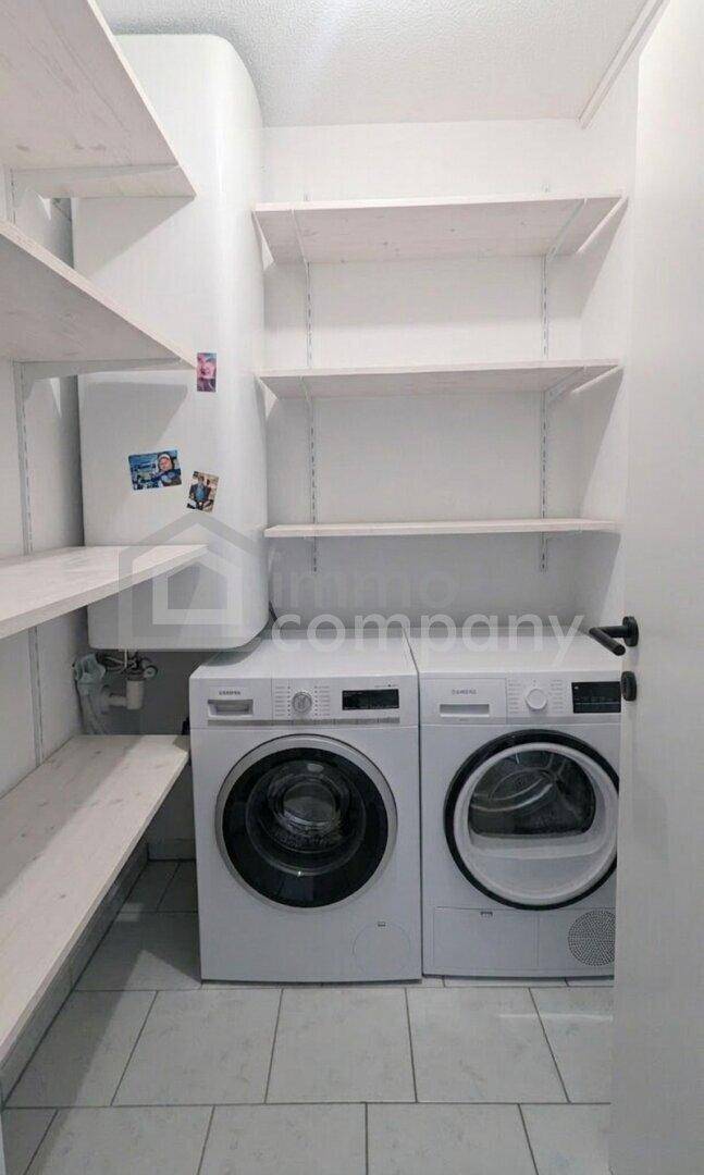 Praktischer Hauswirtschaftsraum mit Waschmaschine, Trockner und Regalen für zusätzlichen Stauraum.