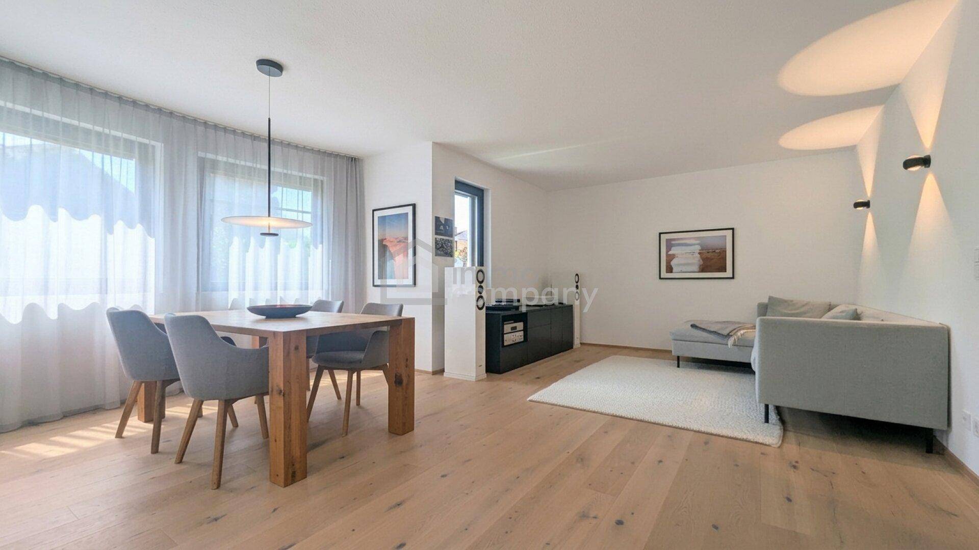 Geräumiger Wohn- und Essbereich mit großen Fenstern, hellem Holzboden und moderner Einrichtung.