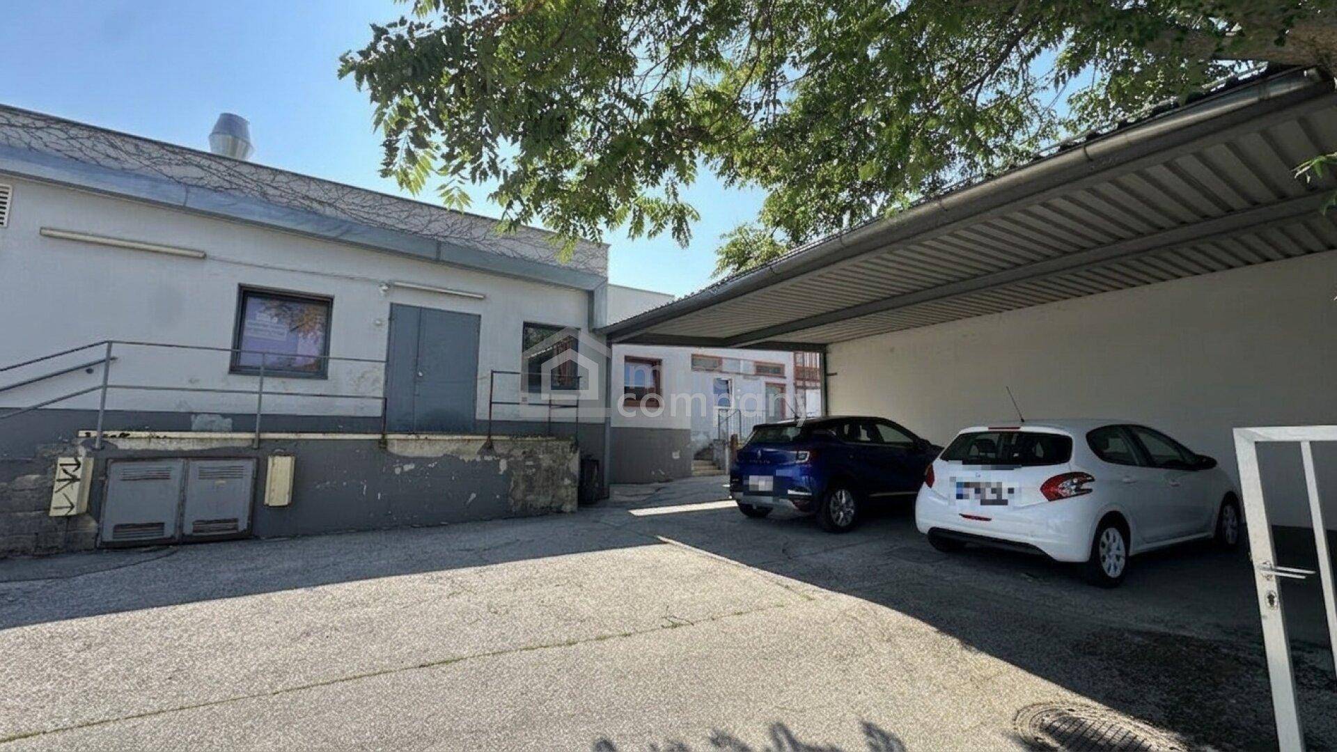 Hinterhofbereich mit Carport für Fahrzeuge und Zugang zum Gebäude.