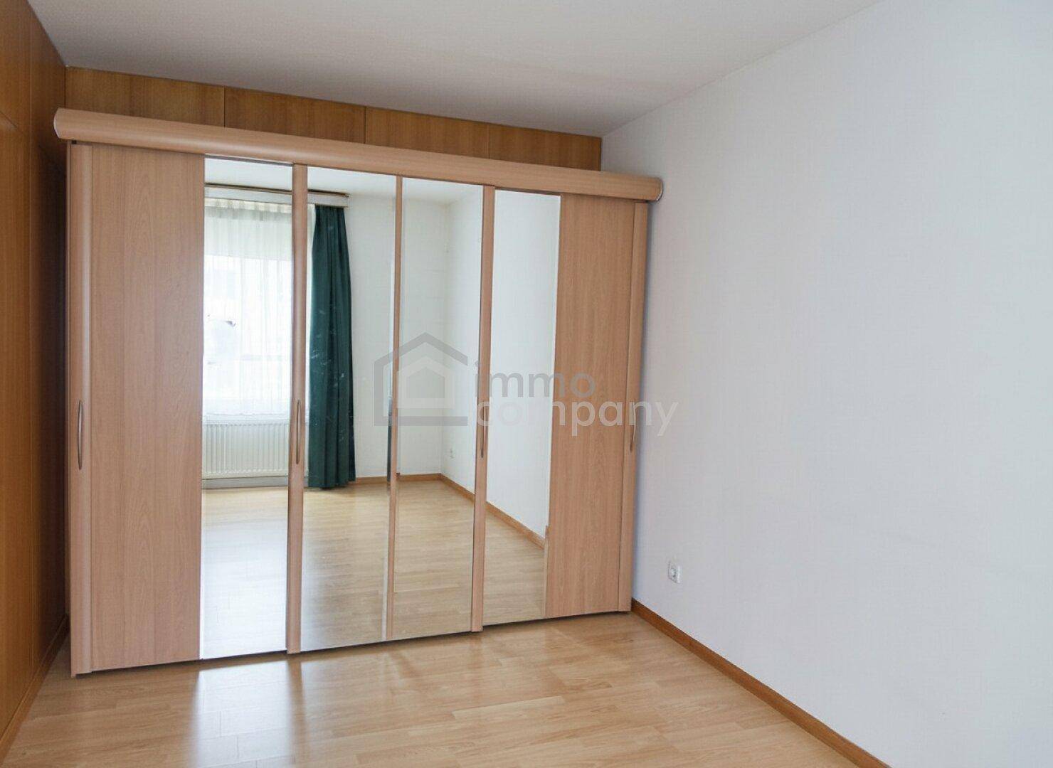 Schlafzimmer mit hellem Holzboden und großem Spiegelschrank, der den Raum optisch vergrößert.