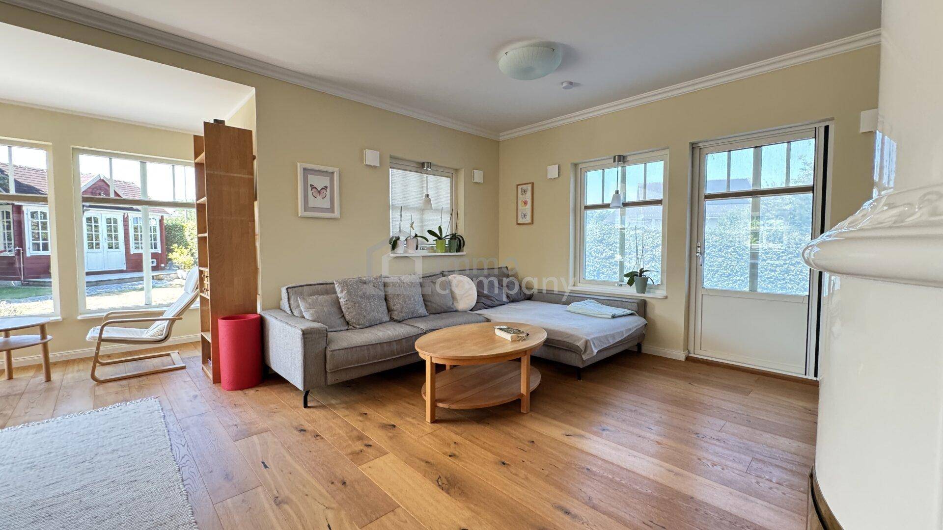Geräumiges Wohnzimmer mit L-förmigem Sofa, Holzboden und Blick in den Garten.