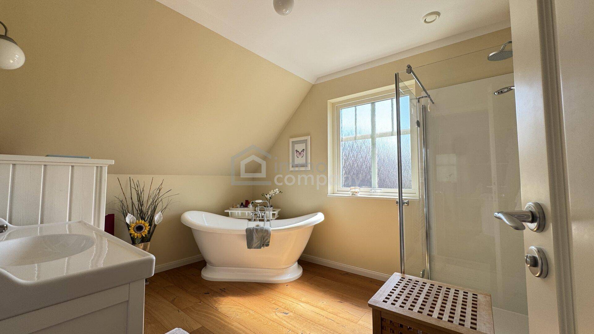 Modernes Badezimmer mit freistehender Badewanne, Dusche und Holzboden unter Dachschräge.