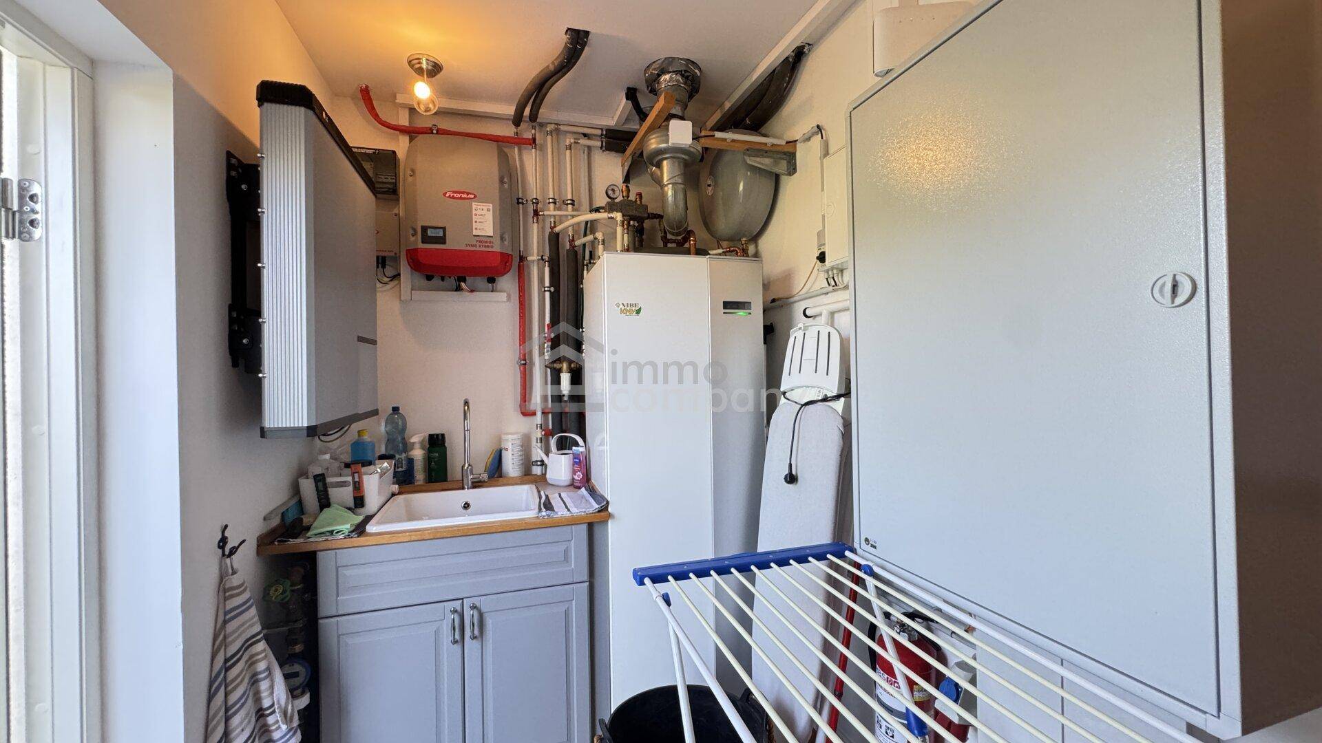 Praktischer Hauswirtschaftsraum mit Waschbecken, Heizungsanlage und Trockenständer.