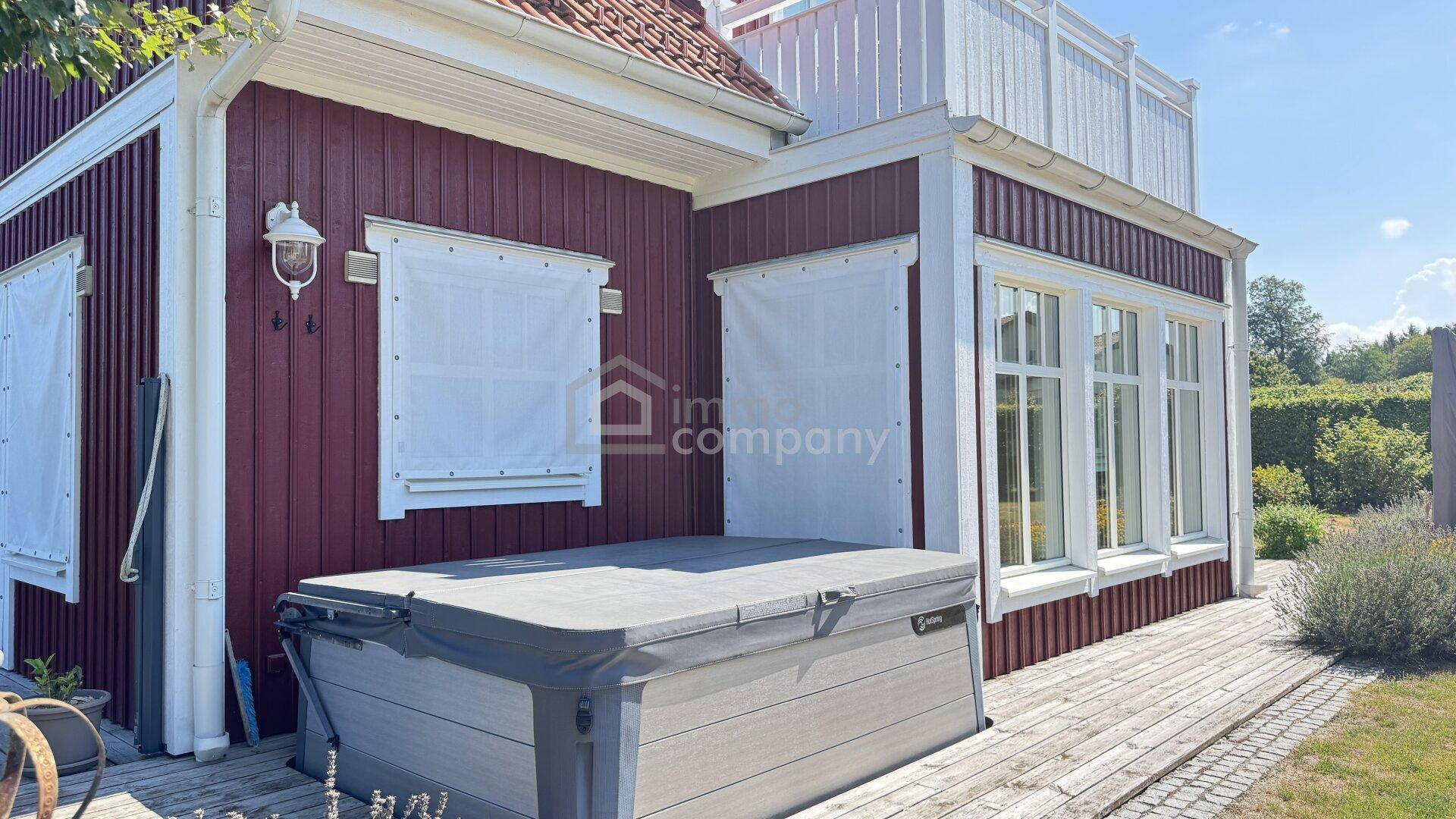 Außenbereich mit Whirlpool auf einer Holzterrasse neben dem Haus.