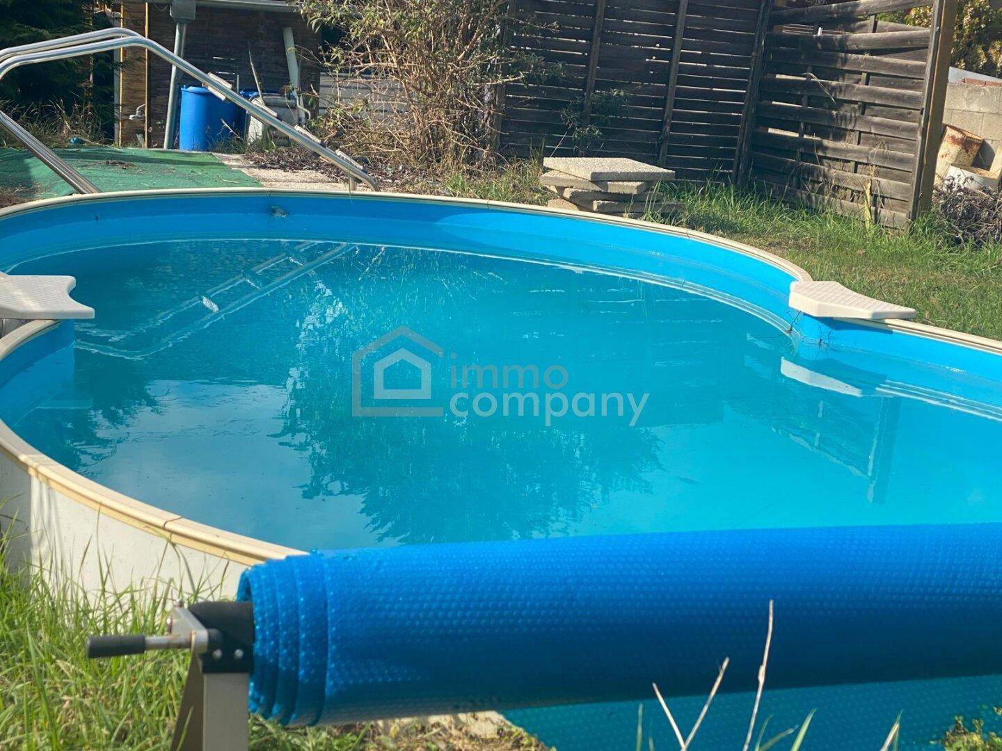Nahaufnahme eines Aufstellpools mit blauer Abdeckung und Leiter im grünen Gartenbereich.