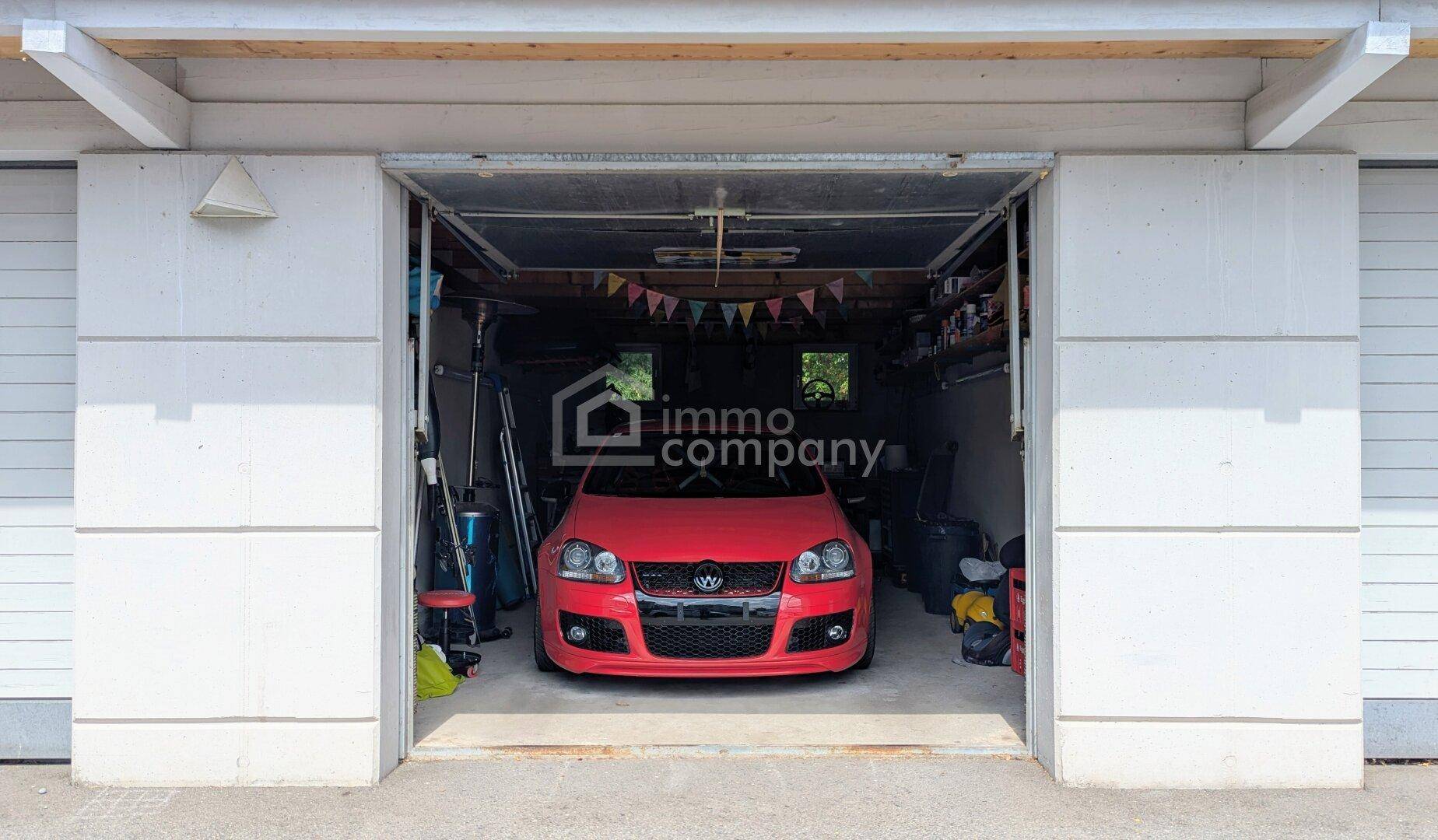 Geräumige Garage mit einem roten Auto und Stauraum.