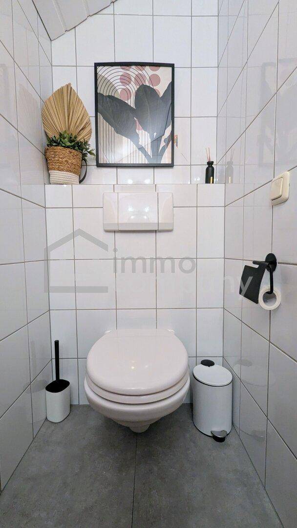 Kleines Gäste-WC mit weißen Fliesen und wandhängender Toilette.