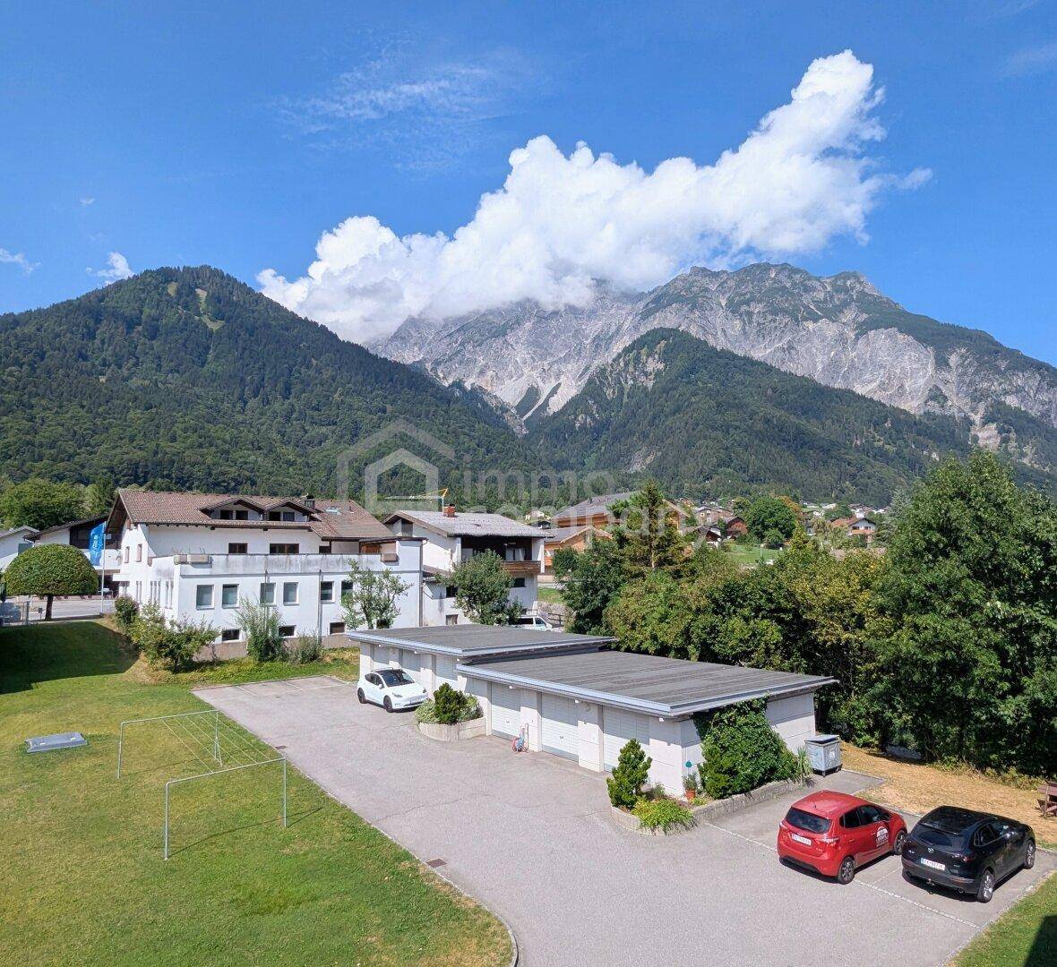 Außenansicht des Gebäudes mit Garagen und majestätischem Bergblick.