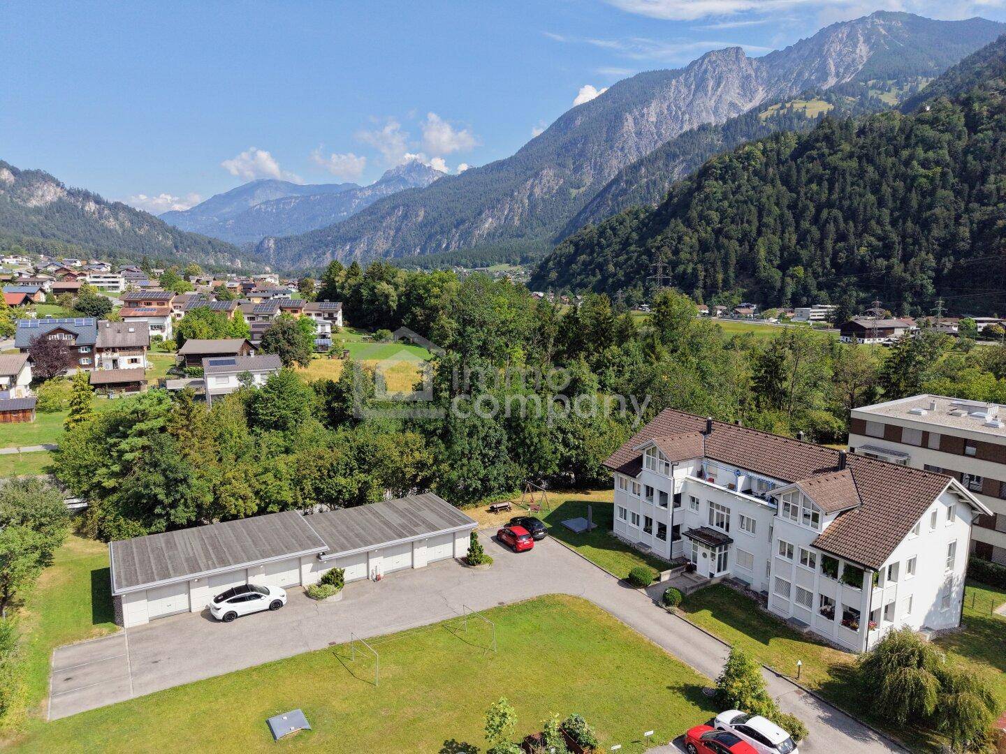 Luftaufnahme des Wohnkomplexes mit Garagen und beeindruckender Bergkulisse.