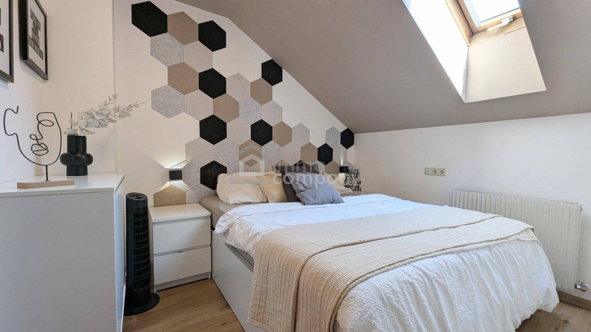 Gemütliches Schlafzimmer mit modernem Wanddekor, Dachfenster und schräger Decke.