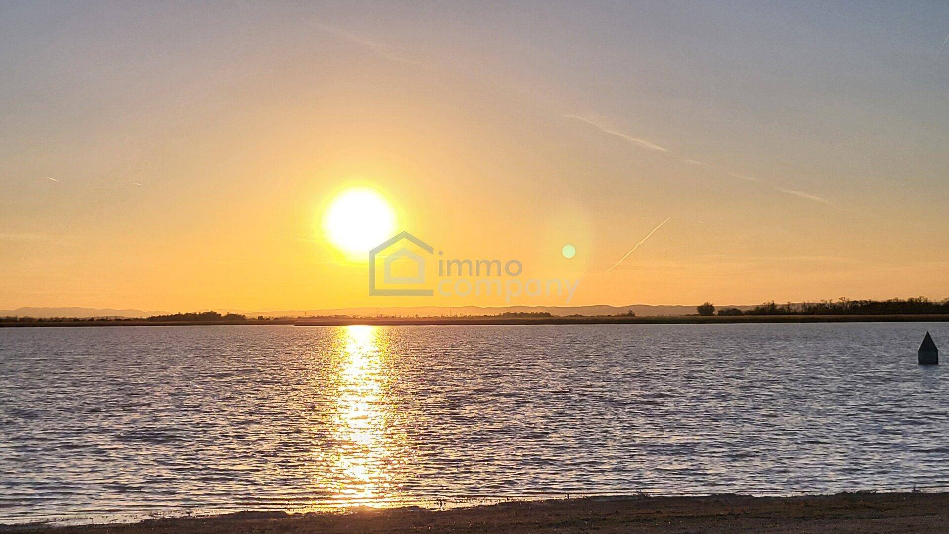 Malerischer Sonnenuntergang über einem ruhigen See mit weitem Blick auf die Landschaft.