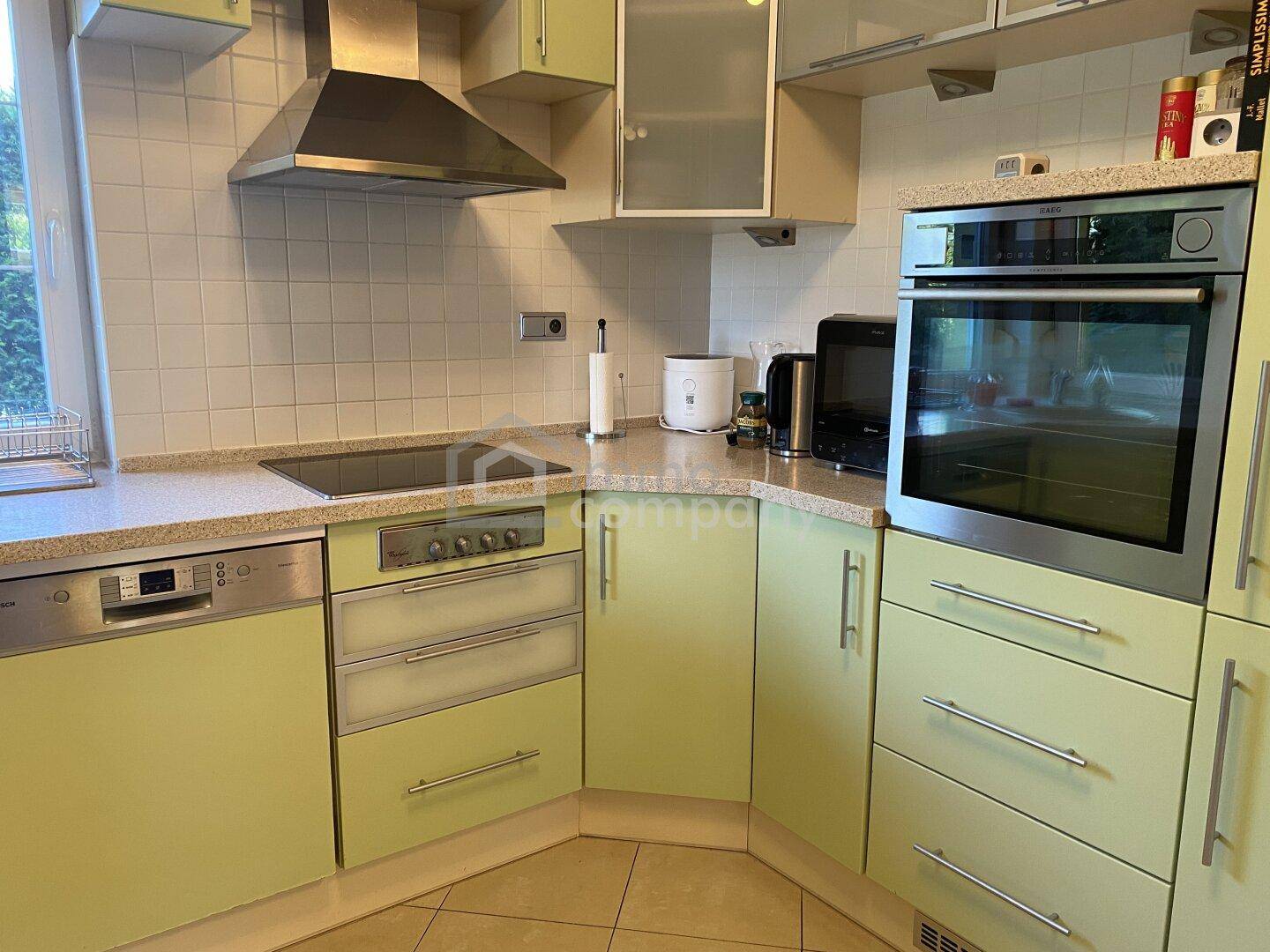 Funktionale Küche mit hellgrünen Schränken, integrierten Geräten und Fenster für Tageslicht.
