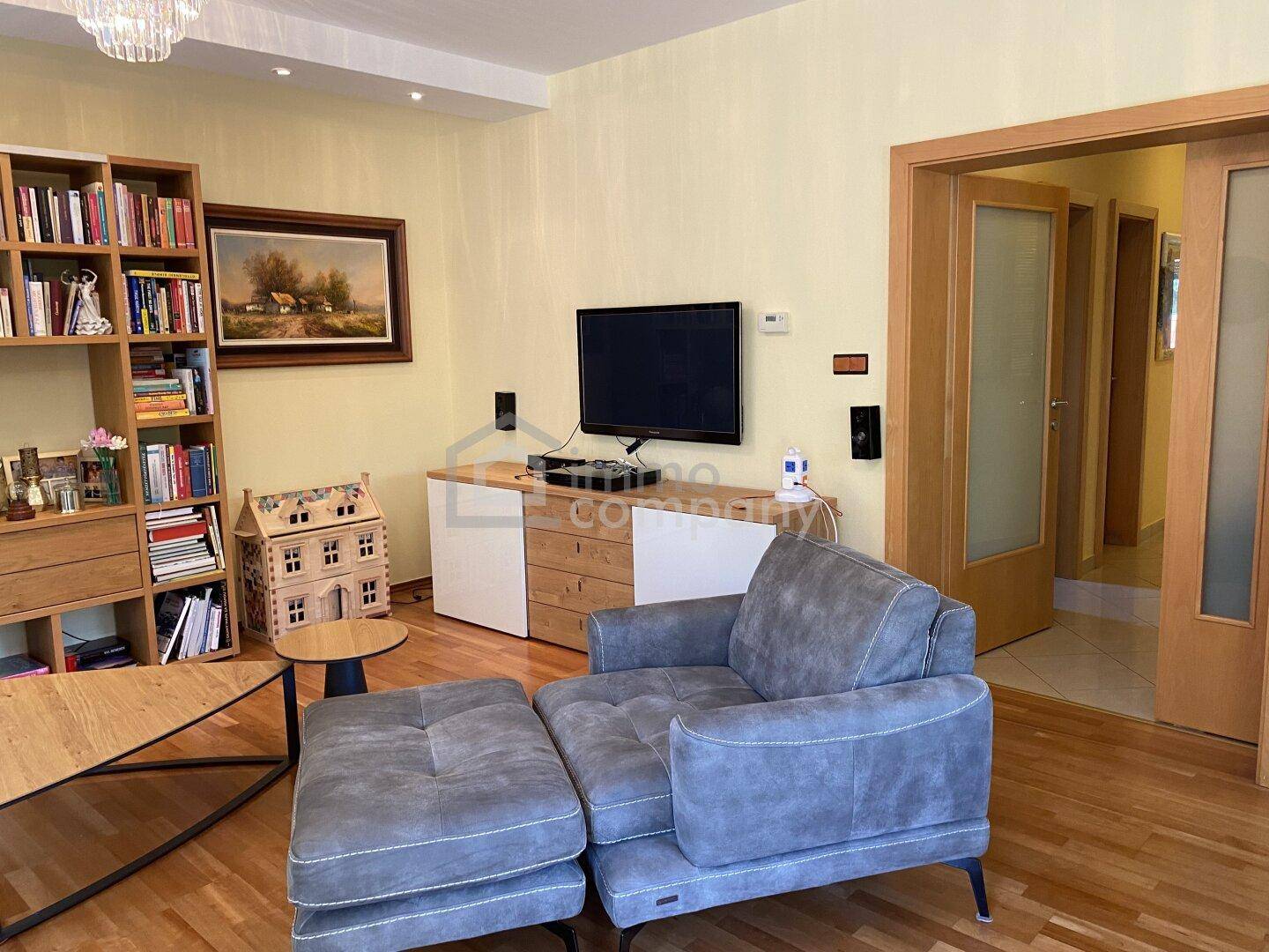 Wohnbereich mit Fernseher, bequemen Sesseln und einem Bücherregal, ideal zum Entspannen.