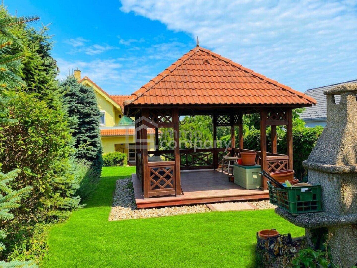 Rustikaler Holzpavillon im grünen Garten, ideal für entspannte Stunden im Freien.