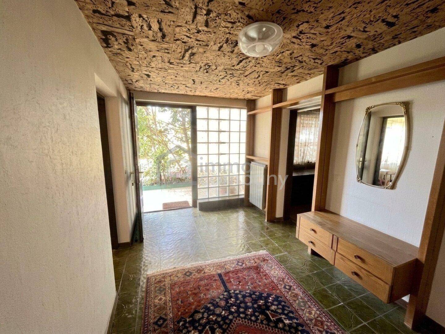 Eingangsbereich mit grünen Fliesen, Holzelementen und einer auffälligen Korkdecke, die einen warmen Empfang bietet.