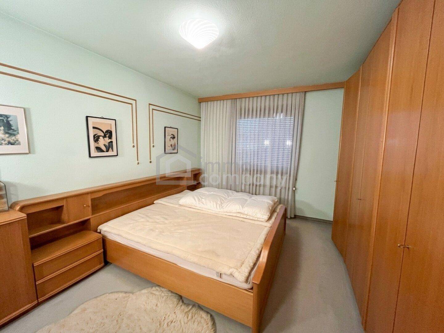Schlafzimmer mit einem Holzbett, praktischen Einbauschränken und hellgrünen Wänden, die eine ruhige Atmosphäre schaffen.