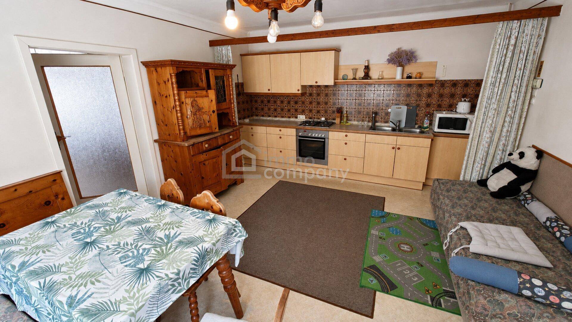 Gemütliche Wohnküche mit hellen Holzschränken, Esstisch und einer kleinen Sitzecke.