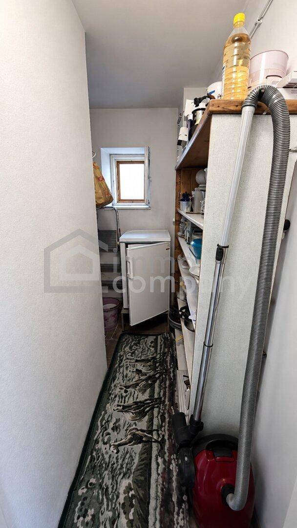 Schmaler Abstellraum mit Regalen, einem kleinen Fenster und Stauraum für Haushaltsgeräte.